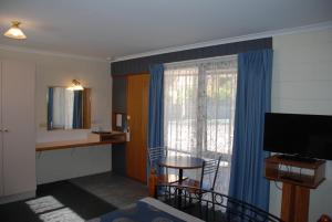 ein Hotelzimmer mit einem Tisch und einem Fenster in der Unterkunft Cunningham Shore Motel in Lakes Entrance