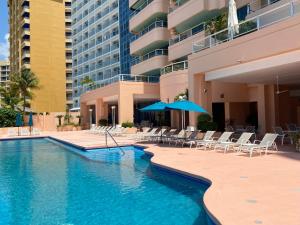 a swimming pool with chairs and umbrellas next to a building at Comfortable Beachfront apartment in Acapulco in Acapulco