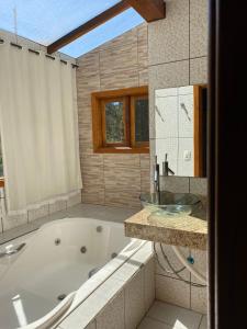 a large bathroom with a tub and a sink at Pousada Vale Verde in Monte Verde