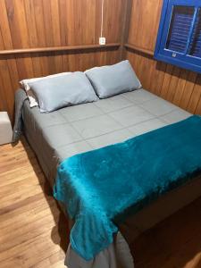 ein Bett in einem Zimmer mit einer blau-weißen Decke in der Unterkunft CASA DE CAMPO FAZENDA DAS PELOTAS in Bom Jardim da Serra