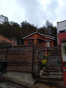 a house with a wooden fence in front of it at Cabaña Los Nogales in Pátzcuaro