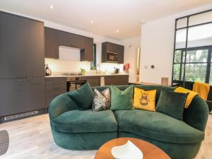 a living room with a green couch and a kitchen at The Observatory Annexe in Dorking