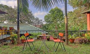 a patio with a table and chairs and a palm tree at Itsy Hotels Vailankanni Natures Inn in Panaji