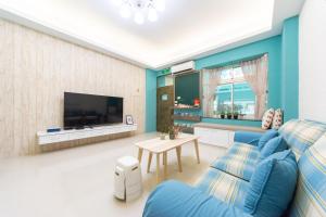 sala de estar con sofá azul y TV en 向晴民宿 花蓮市包棟民宿 en Hualien