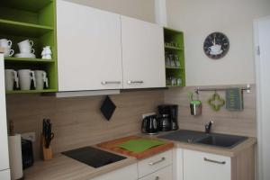 eine Küche mit grünen und weißen Schränken und einem Waschbecken in der Unterkunft Villa Fanny in Sassnitz