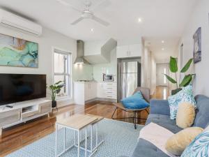 a living room with a blue couch and a tv at Trinity Beach House in Rosebud