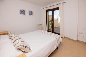 a white bed in a room with a window at Drac Blanc 1-4 in Cala Ratjada +16 photos