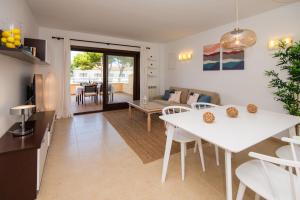 cocina y sala de estar con mesa blanca y sillas en Drac Blanc 1-4, en Cala Ratjada