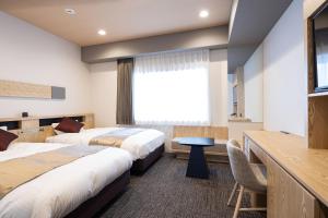 a hotel room with two beds and a window at Hotel Grand Cocoe Kurashiki in Kurashiki