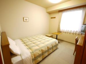 a bedroom with a bed and a window at Hotel Route-Inn Jouetsu in Joetsu