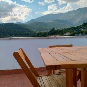 a wooden table and chairs on a balcony with mountains at Enjoy Gredos in El Arenal