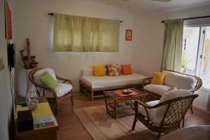 uma sala de estar com um sofá e cadeiras em Sunbird Bungalow em Anse Boileau