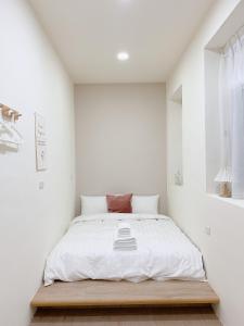 a white bedroom with a bed with a wooden platform at Cozy Homestay in Tainan