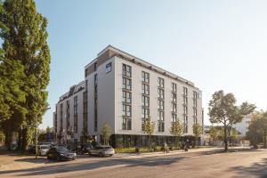 a large white building with cars parked on a street at the niu Brass in Munich