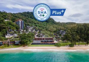 een hotel op een strand met een bord waarop shka plus staat bij The Naka Phuket, a Member of Design Hotels - SHA Extra Plus in Kamala Beach
