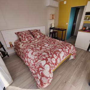 1 dormitorio con 1 cama con edredón rojo y blanco en La Cabane de Lili Prune, en Goudargues