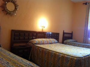 pokój hotelowy z dwoma łóżkami i lustrem w obiekcie Hostal Paracuellos w mieście Paracuellos de Jarama