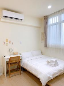 a white bedroom with a bed and a desk at Cozy Homestay in Tainan
