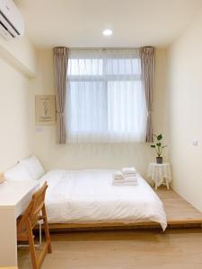 Un dormitorio con una cama blanca y una ventana. en Cozy Homestay, en Tainan