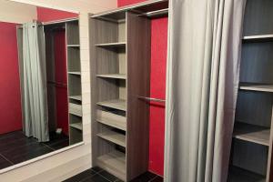 a walk in closet with red walls and a mirror at Appartement en entrée de ville avec balneo in Pont-lʼAbbé