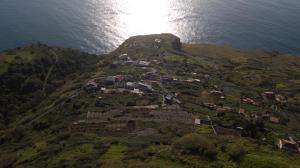 a small village on a hill near the ocean at Refúgio de Pedra in Fajã da Ovelha