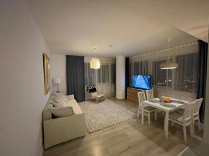 a living room with a couch and a table and a tv at 34 floor at the top of the Baltic in Klaipėda