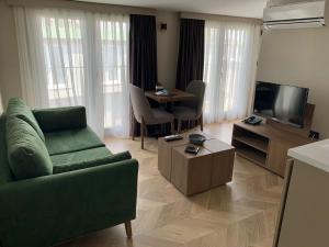 a living room with a green couch and a television at Istanbul Park Hotel in Tuzla