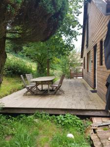 una terraza de madera con mesa y sillas. en Appartement cosy calme à l'orée du bois, en Cornimont
