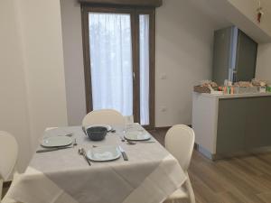 a table with white chairs in a room with a kitchen at A DUE PASSI BED & BREAKFAST in Troia