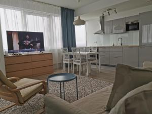 a living room with a couch and a table and a kitchen at 34 floor at the top of the Baltic in Klaipėda