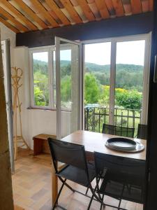 comedor con mesa, sillas y ventanas en Les Genêts de la Valdaine, en Rochefort-en-Valdaine