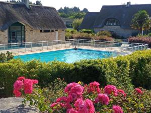 uma piscina em frente a uma casa com flores cor-de-rosa em Appartement de standing dans le Golf International de La Baule em Saint-André-des-Eaux