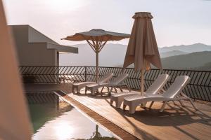 a group of chairs and an umbrella on a deck at Encosta de Louredo by Pousadela Village in Vieira do Minho