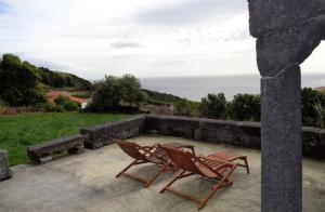 2 sillas sentadas en un patio con vistas al océano en Casa da Alícia, en Feiteira