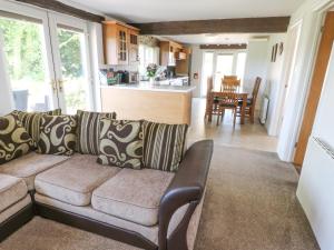 a living room with a couch and a kitchen at Rhosydd Cottage in Llanallgo