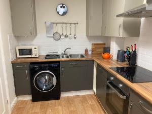 a kitchen with a washing machine and a microwave at Peak House in Ilkeston