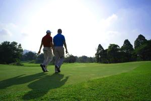 dos hombres caminando en un campo de golf en Espira Kinrara, en Puchong