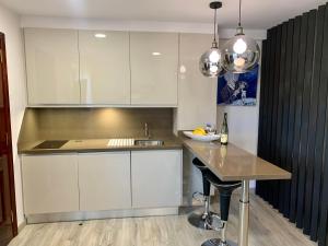 eine Küche mit weißen Schränken und einem Tisch mit einer Spüle in der Unterkunft Apartamento Tahoro in La Orotava