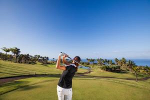a woman swinging a golf club on a golf course at Las Terrazas de Abama Suites in Guía de Isora