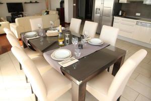 - une table à manger avec des chaises blanches et une bouteille de vin dans l'établissement Apartment Toma, à Kučine