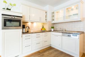 eine weiße Küche mit weißen Schränken und Geräten in der Unterkunft Seemöwe - Villa Helene mit Meerblick in Top Lage in Binz