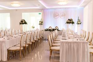 a row of tables with white tablecloths and flowers at Restauracja Venus in Ostrowiec Świętokrzyski +5 photos