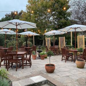 eine Terrasse mit Tischen, Stühlen und Sonnenschirmen in der Unterkunft The Scotts Arms Village Inn in Sicklinghall