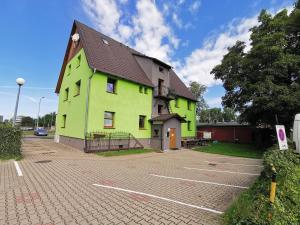a yellow and green building with a parking lot at Zielony Dom in Bolesławiec