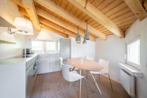 a kitchen with a wooden table and white chairs at COCOON - Laax in Laax