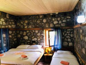 two beds in a room with a wall of rocks at Guest house Hyrmet Demushi in Valbonë