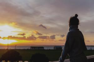 Una persona in piedi su un cornicione che guarda il tramonto di The Queens Hotel a Portsmouth