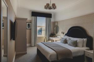Un dormitorio con una cama grande y una ventana en The Queens Hotel en Portsmouth