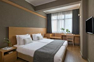 um quarto de hotel com uma cama grande e uma secretária em Porto Palace Hotel Thessaloniki em Tessalónica