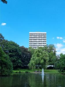 un grand bâtiment en face d'un étang avec une fontaine dans l'établissement PLAZA Hotel Gelsenkirchen, à Gelsenkirchen